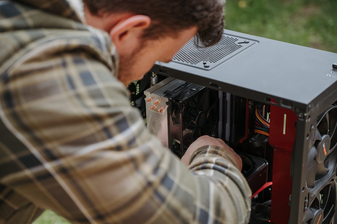 A man cleans and maintains a desktop PC outdoors with precision.