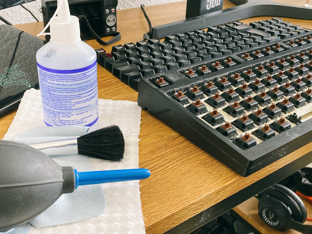 Set of tools and cleaning products for mechanical keyboard maintenance on a wooden desk.